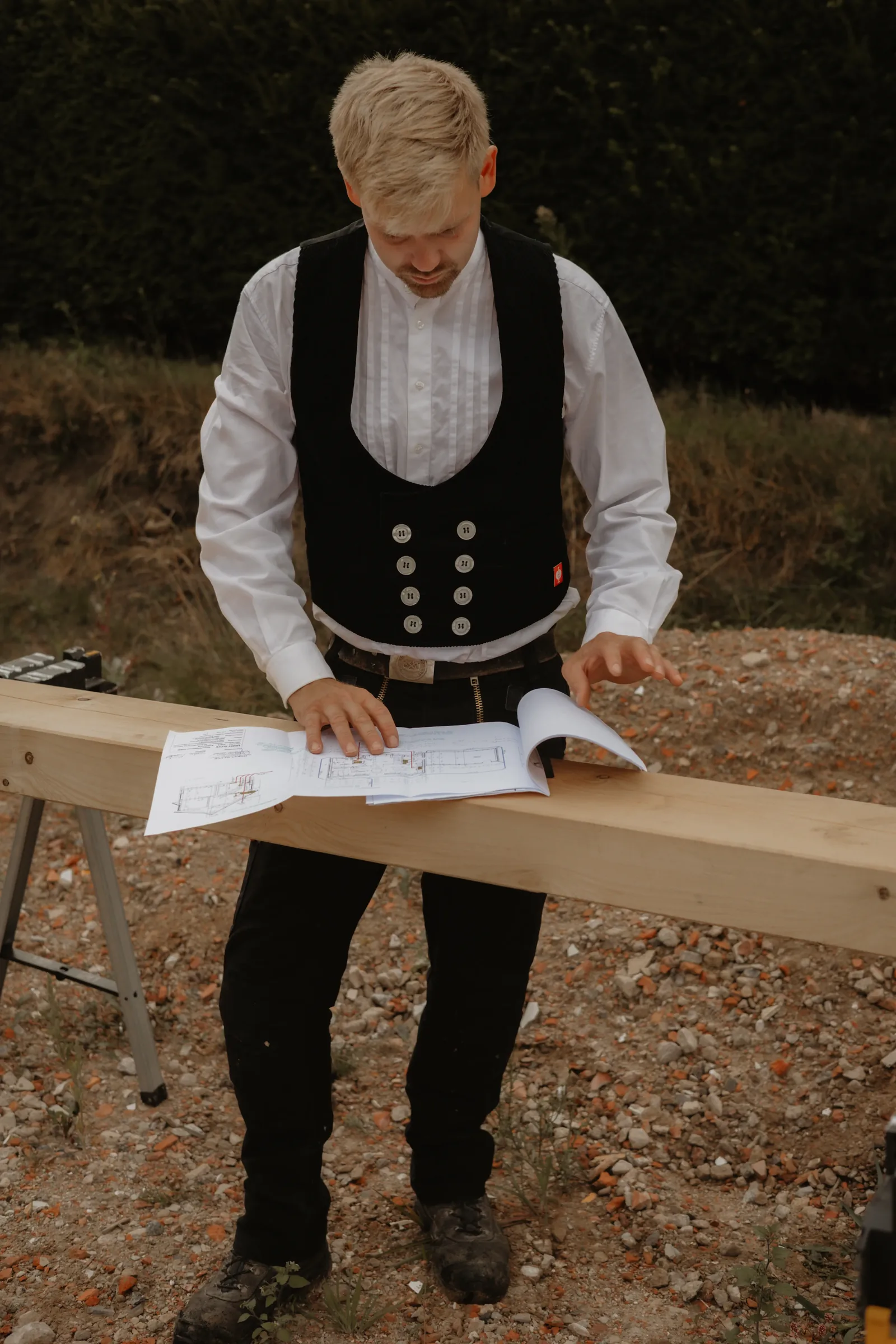 Zimmerer prüft Baupläne auf einem Holzbalken